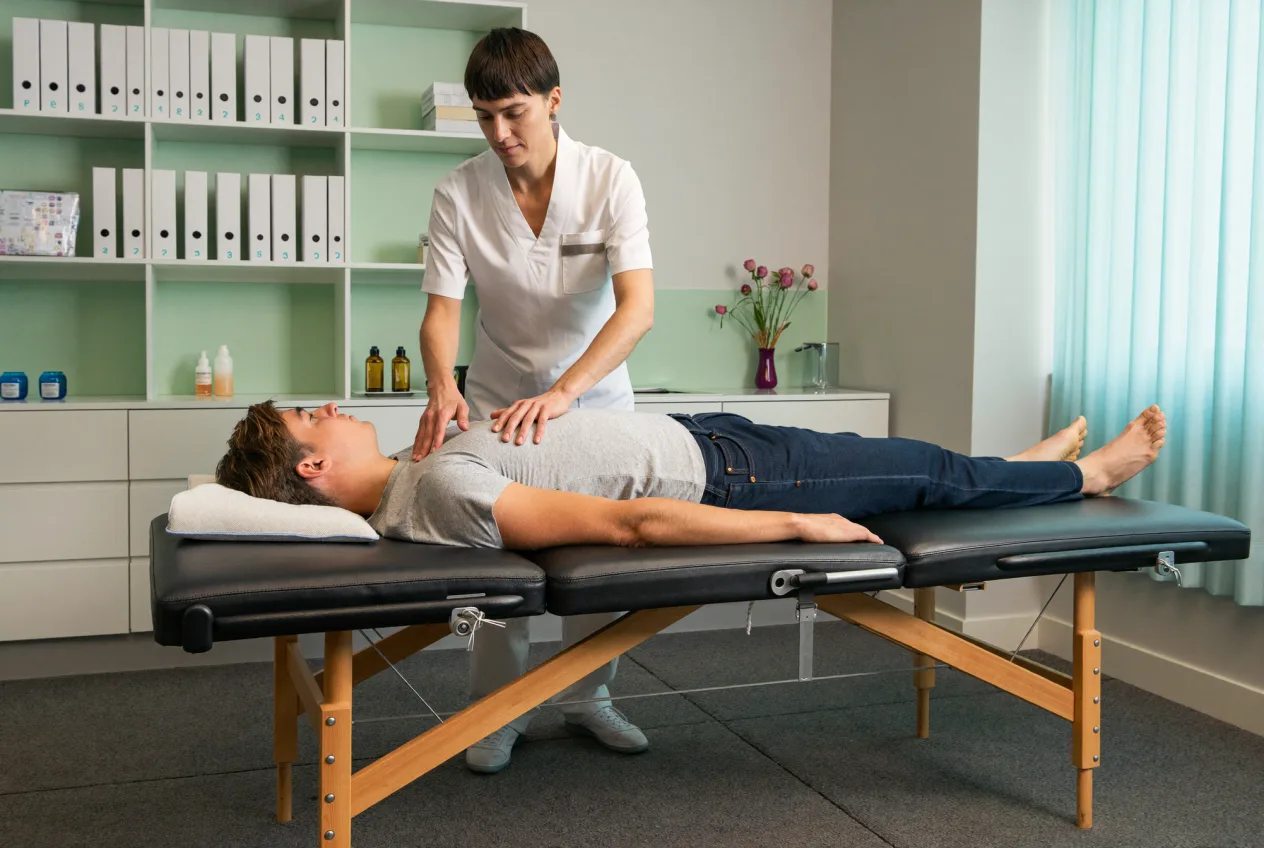 Physiotherapeutin behandelt einen Patienten im hellen Behandlungsraum